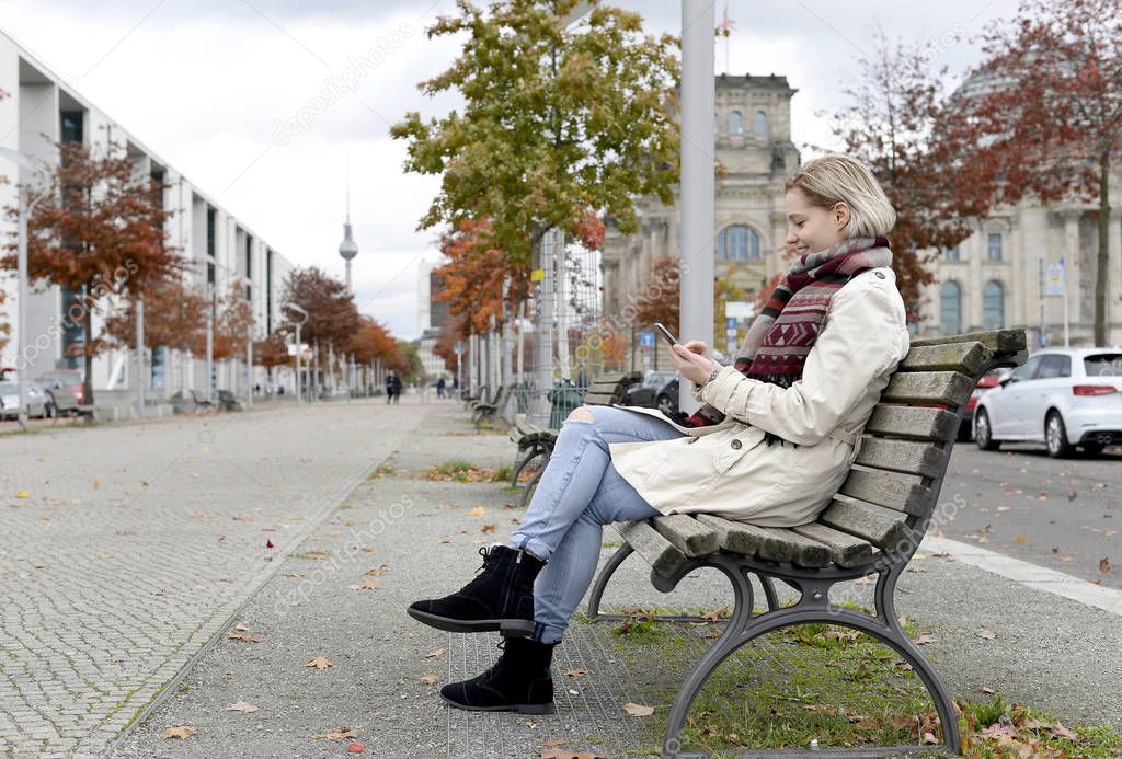 beautiful young woman with smartphone sitting on bench