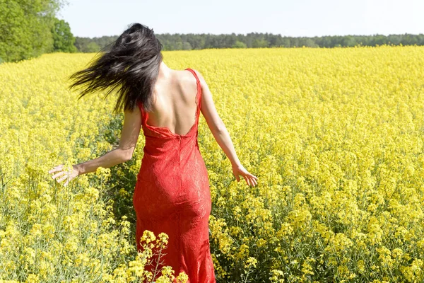 菜の花畑 リアビューで幸せな若い女 — ストック写真