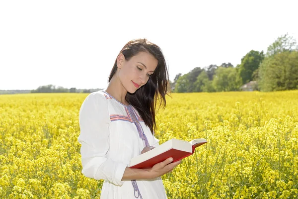 若い女性は 菜の花畑で本を読んで — ストック写真