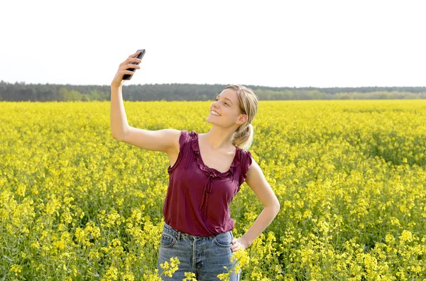 快乐的年轻金发女子自拍与智能手机 — 图库照片