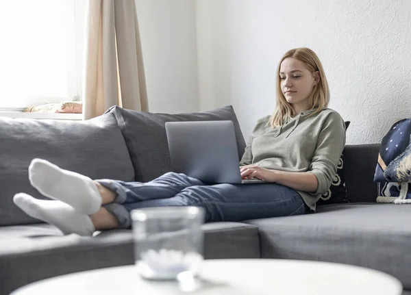 young woman with laptop lying on couch