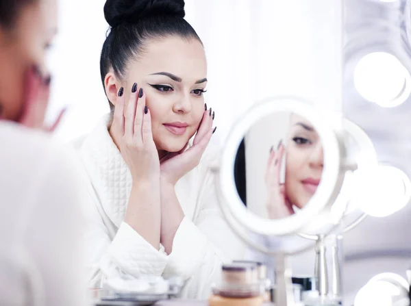 Portrait d'une femme brune se maquillant devant le miroir — Photo