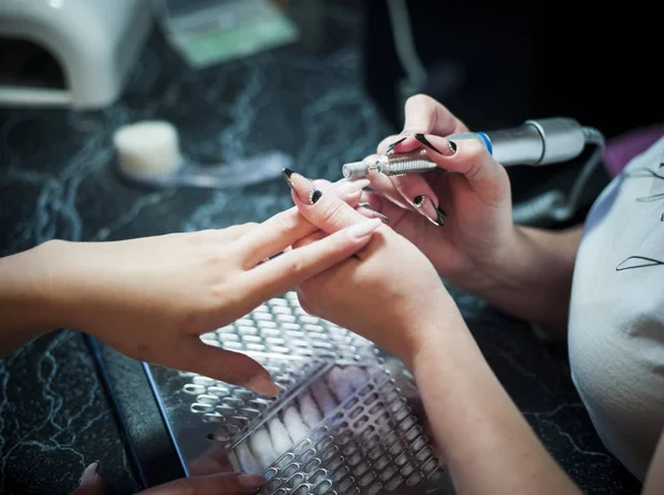 Mujer en un salón de uñas recibiendo una manicura por una esteticista — Foto de Stock