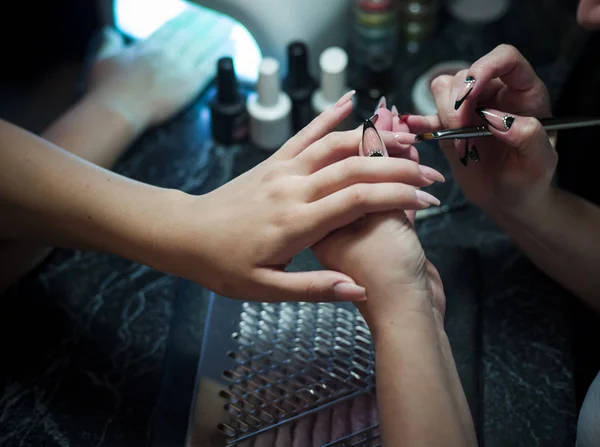 Mujer en un salón de uñas recibiendo una manicura por una esteticista — Foto de Stock