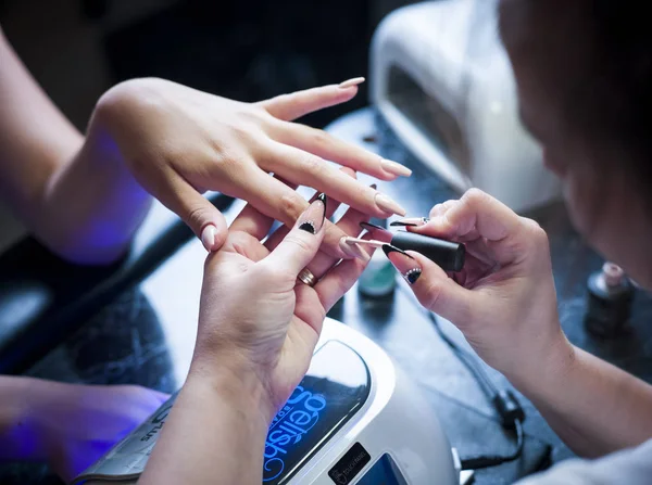 Woman in a nail salon receiving a manicure by a beautician — Stock Photo, Image
