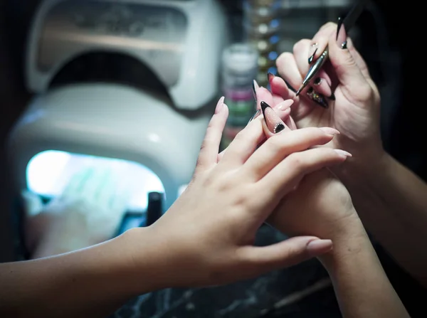 Mujer en un salón de uñas recibiendo una manicura por una esteticista — Foto de Stock