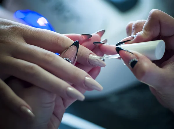 Mujer en un salón de uñas recibiendo una manicura por una esteticista — Foto de Stock