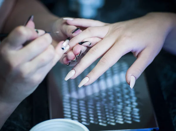 Mujer en un salón de uñas recibiendo una manicura por una esteticista — Foto de Stock