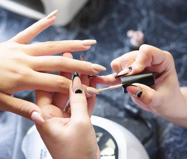 Femme dans un salon de manucure recevant une manucure par un esthéticienne avec lime à ongles femme — Photo