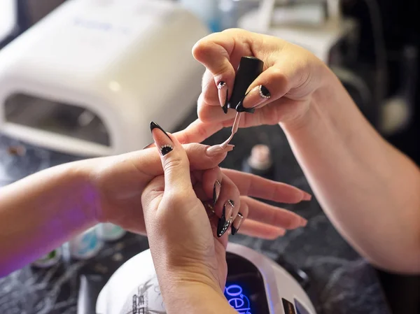 Женщина в маникюрном салоне получает маникюр от косметолога с женщиной с пилкой для ногтей — стоковое фото