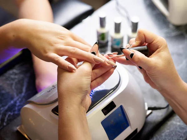 Mujer en un salón de belleza recibiendo una manicura por una esteticista con lima de uñas mujer — Foto de Stock