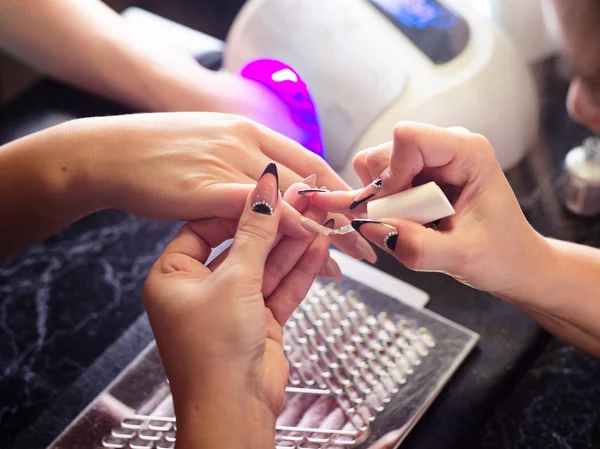 Mujer en un salón de belleza recibiendo una manicura por una esteticista con lima de uñas mujer — Foto de Stock