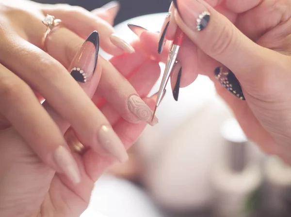 Женщина в маникюрном салоне получает маникюр от косметолога с женщиной с пилкой для ногтей — стоковое фото