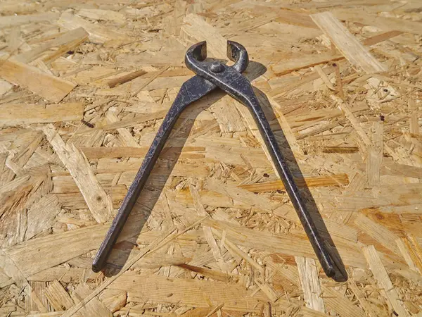 Construction tongs on a wooden background — Stock Photo, Image