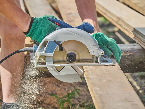 The builder cuts the board with a circular saw