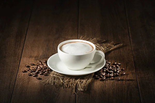 Чашка капучино с кофейными зёрнами — стоковое фото