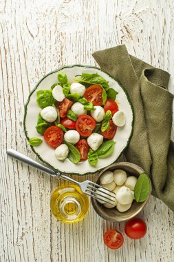 Olgun domatesli lezzetli caprese salatası ve taze fesleğen yapraklı mozzarella peyniri. İtalyan yemeği. Peynirli salata, domates, fesleğen, tuz, karabiber, zeytinyağı.