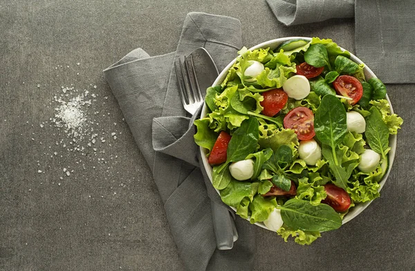 健康的なグリーンレタスサラダトマトとモッツァレラチーズグレーテーブルの背景 — ストック写真