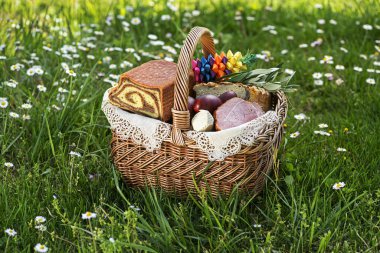 Geleneksel paskalya yemekleri, jambon, yumurta ve ekmek sepeti. Tatil arka planı dışarıda. Paskalya sepeti her çeşit lezzetli şarküteriyle dolu Paskalya yemeği için hazır..