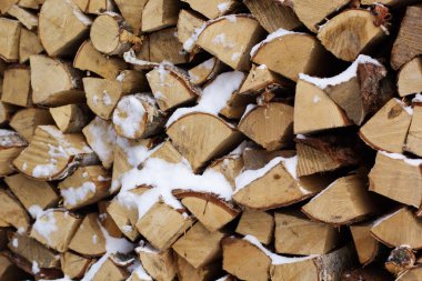 Bir yığın kar ile kıyılmış yakacak odun günlükleri