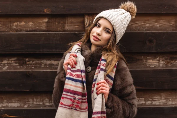 Kız şapka ve atkı ahşap duvar yakınındaki giyiyor