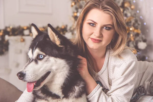 Girl with husky dog in bed near Christmas tree — Stock Photo, Image