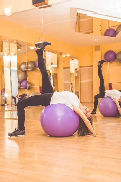 Schlanke hübsche Frau mit lila Fitball im Fitnessstudio — Stockfoto