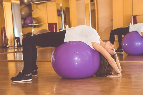 Szczupła ładna kobieta z fioletowy fitball w siłowni — Zdjęcie stockowe