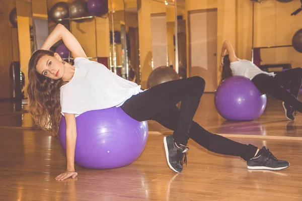 Slim pretty woman with purple fitball in gym — Stock Photo, Image