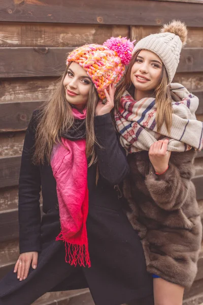 Las niñas están usando ropa de invierno cerca de la pared de madera —  Fotos de Stock