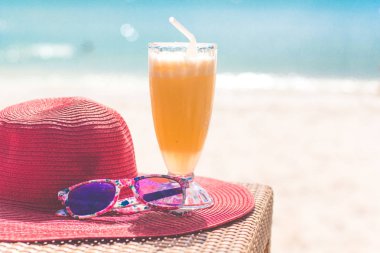 Orange fresh juice, hat and sunglasses near sea clipart