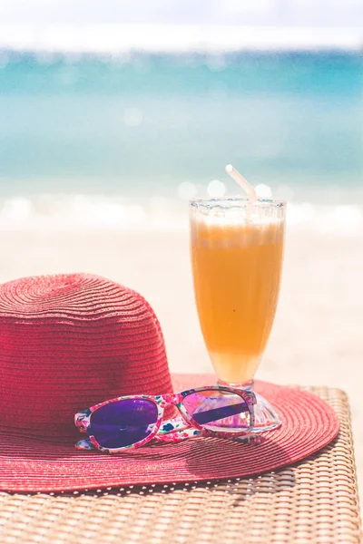 Sumo fresco de laranja, chapéu e óculos de sol perto do mar — Fotografia de Stock