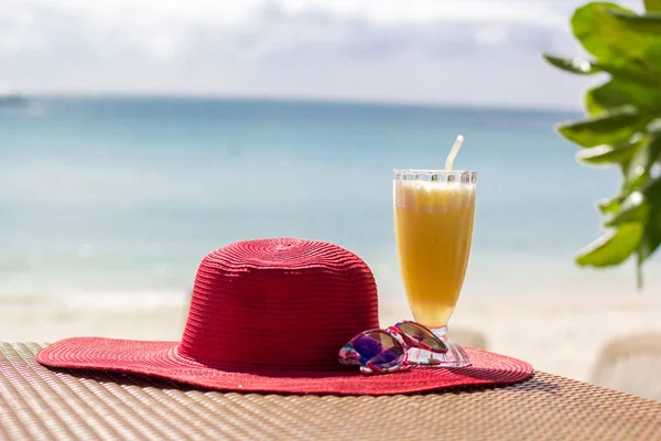 Taze portakal suyu, şapka ve güneş gözlüğü deniz üzerinde — Stok fotoğraf