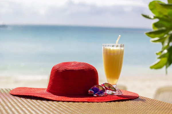 Taze portakal suyu, şapka ve güneş gözlüğü deniz üzerinde — Stok fotoğraf