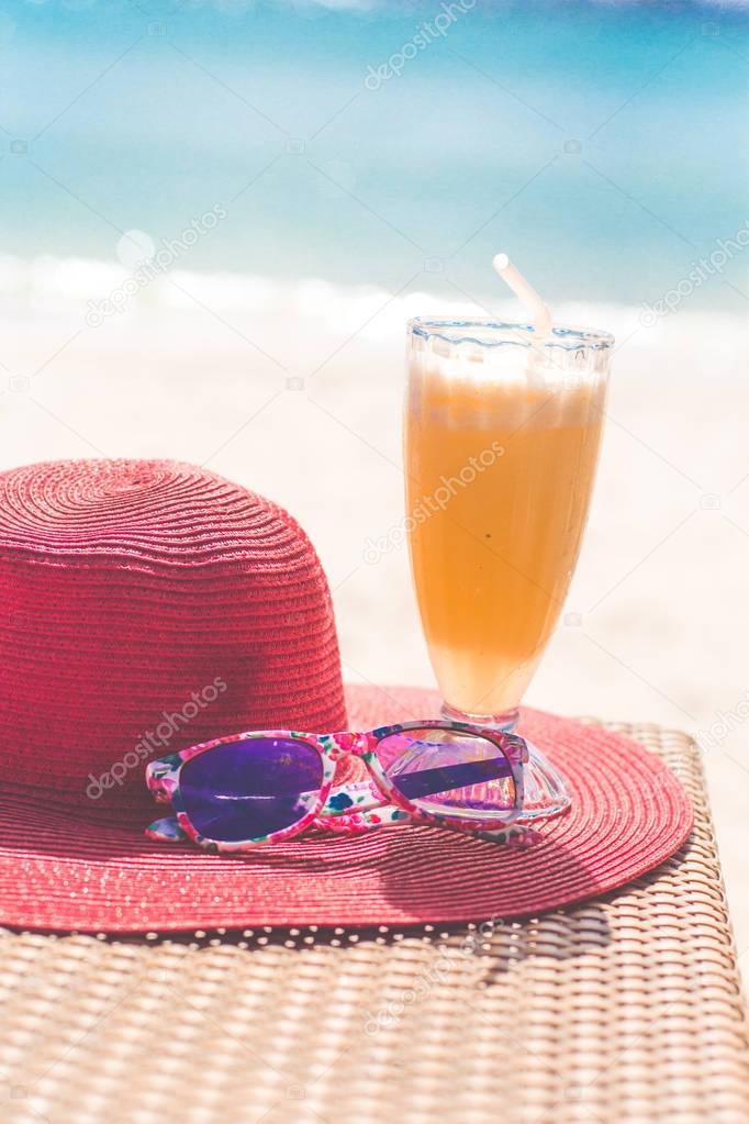 Orange fresh juice, hat and sunglasses over sea — Stock Photo © _chupacabra_ 141980804