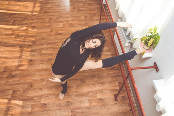 Mujer está estirando sus piernas cerca de banco de ballet —  Fotos de Stock