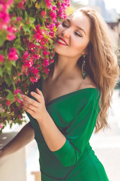 微笑的年轻女子附近绽放粉红色的花朵 — 图库照片
