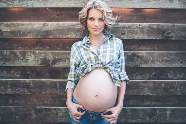 Vacker gravid kvinna bär casual kläder över trävägg — Stockfoto