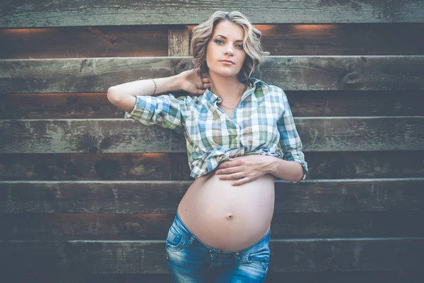 아름 다운 임신한 여자는 나무 벽에 캐주얼 옷을 입으십시오 — 스톡 사진