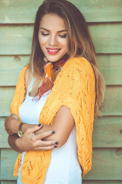 Модна жінка носить жовтий светр на дерев'яному фоні — стокове фото