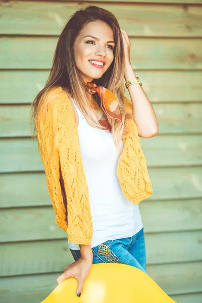 Moda sonriente mujer está usando suéter amarillo sobre fondo de madera al aire libre —  Fotos de Stock