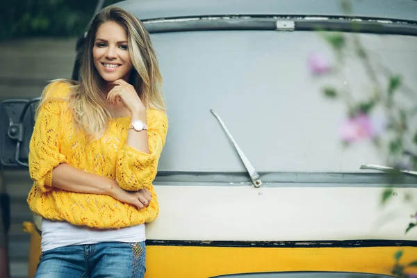 Щаслива усміхнена жінка носить жовтий светр біля старого ретро-автобуса — стокове фото