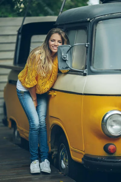 Happy smiling girl is wearing yellow sweater near old retro bus, autumn concept — Stock Photo, Image