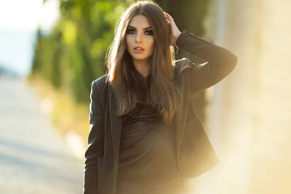 Портрет довольно серьезной деловой женщины носит черную официальную одежду возле деревянной стены на закате — стоковое фото