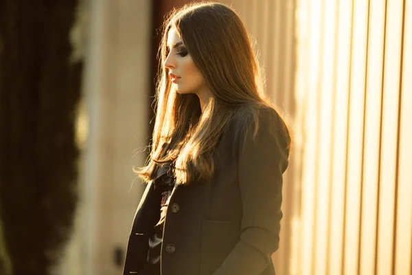 Retrato de mulher de negócios muito séria está vestindo roupas oficiais pretas perto da parede de madeira sobre as luzes do pôr do sol — Fotografia de Stock