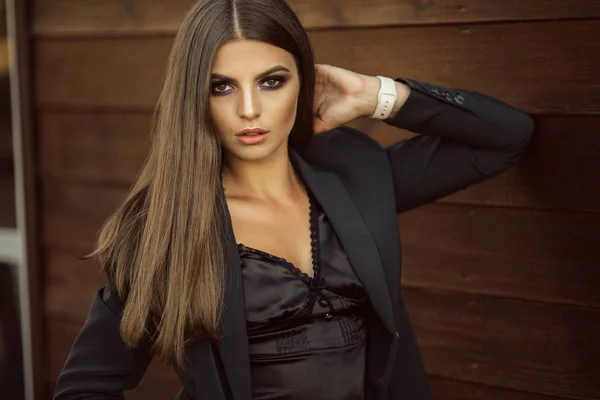 Portrait of fashion serious business woman is wearing black official clothes near wooden wall — Stock Photo, Image