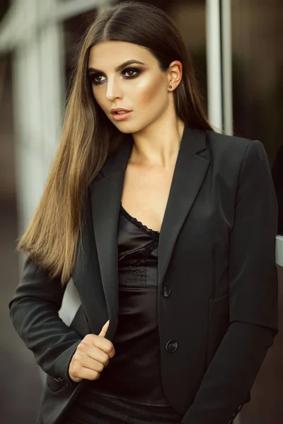 Retrato de moda chica de negocios seria está usando ropa oficial negro cerca de grandes ventanas de vidrio — Foto de Stock