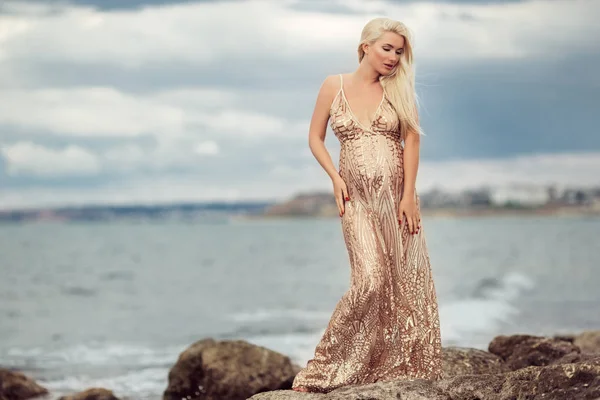Mode gravid kvinna över havet bakgrund bär lyx klänning — Stockfoto