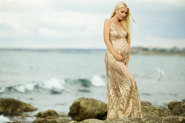 Красивая беременная женщина на морском фоне носит роскошное платье — стоковое фото