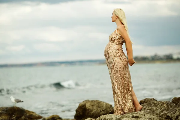 Deniz arka plan üzerinde güzel hamile kadın lüks elbise giyiyor — Stok fotoğraf